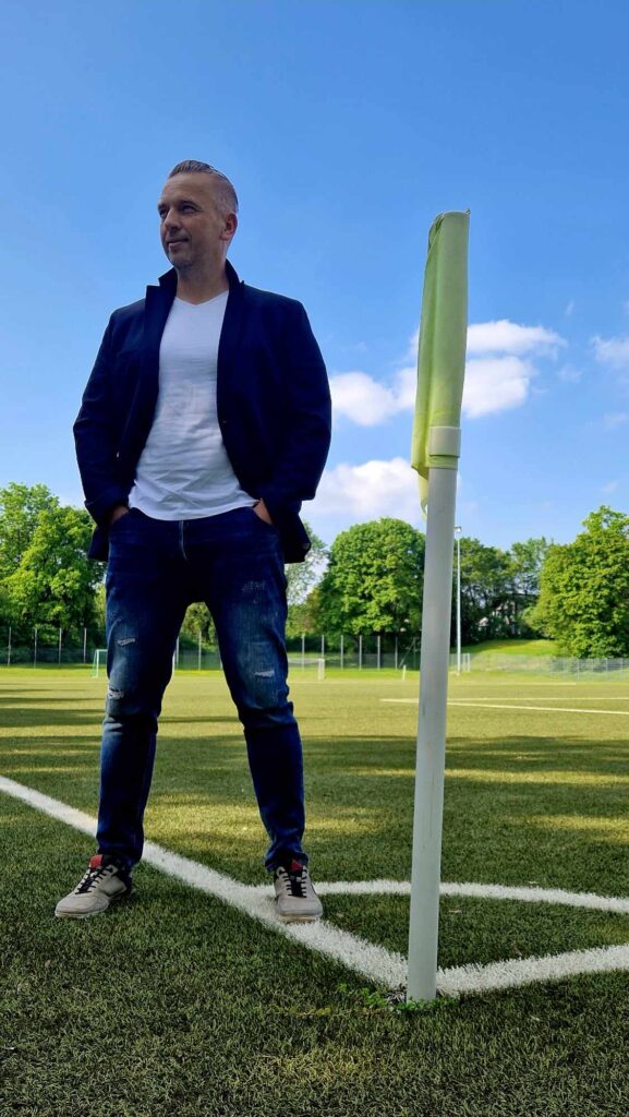 Coach Tomek stojący koło chorągiewki w rogu boiska