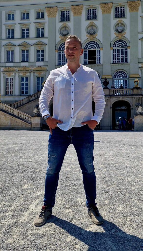 Coach Tomek pewnie stojący przed pałacem